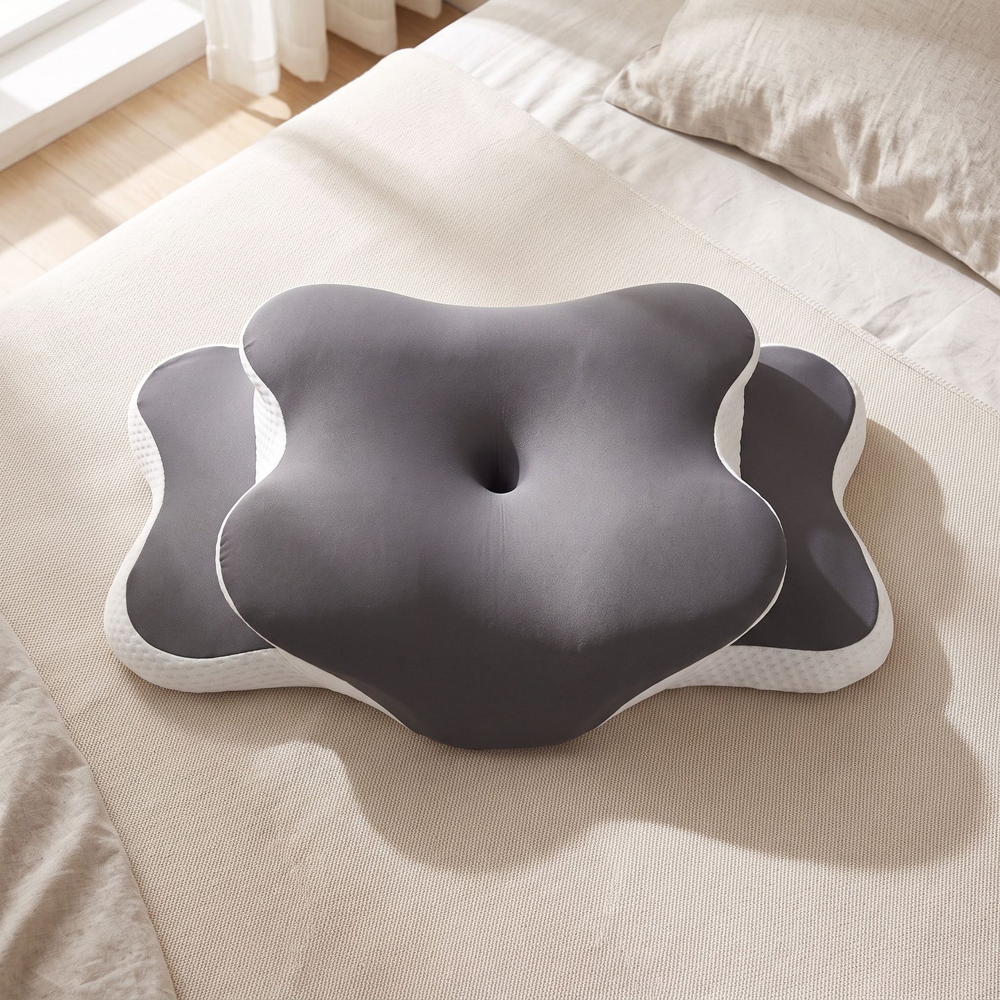 Top-down view of memory foam pillow on neutral bedspread showing ergonomic contours and foam texture with natural sunlight.